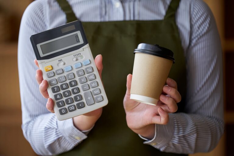 コーヒーと電卓を持つカフェ店員